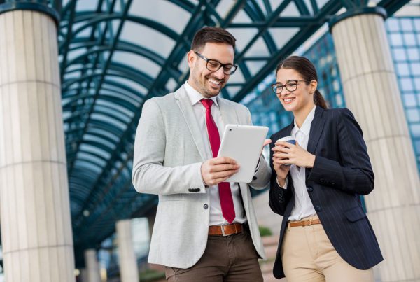 female and male employees laughing at tablet