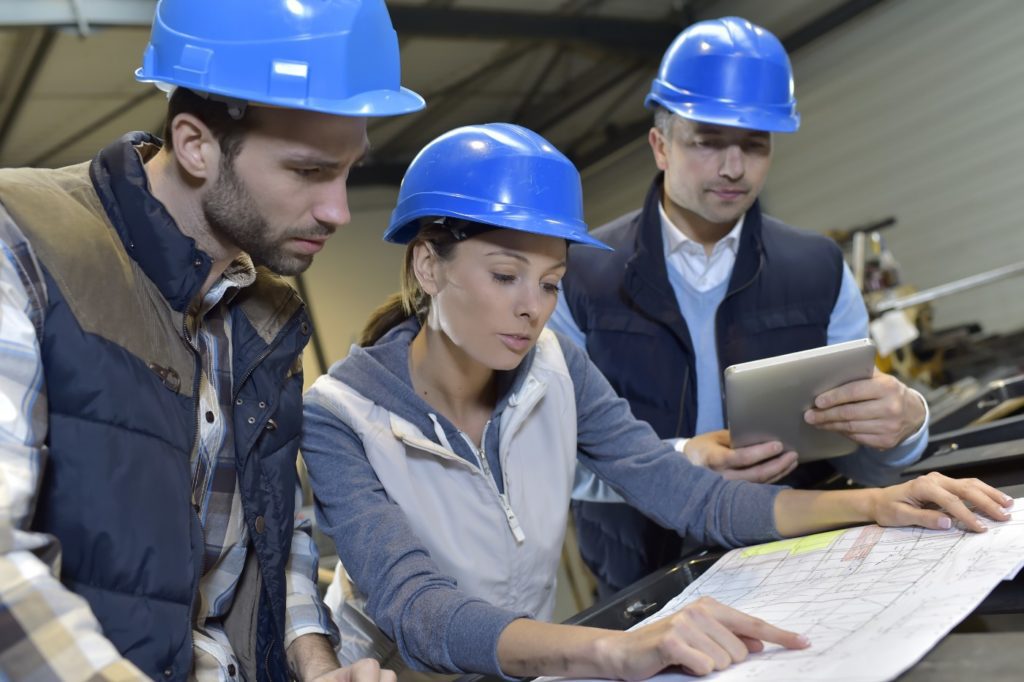 3 employees reviewing blueprints on work site Color